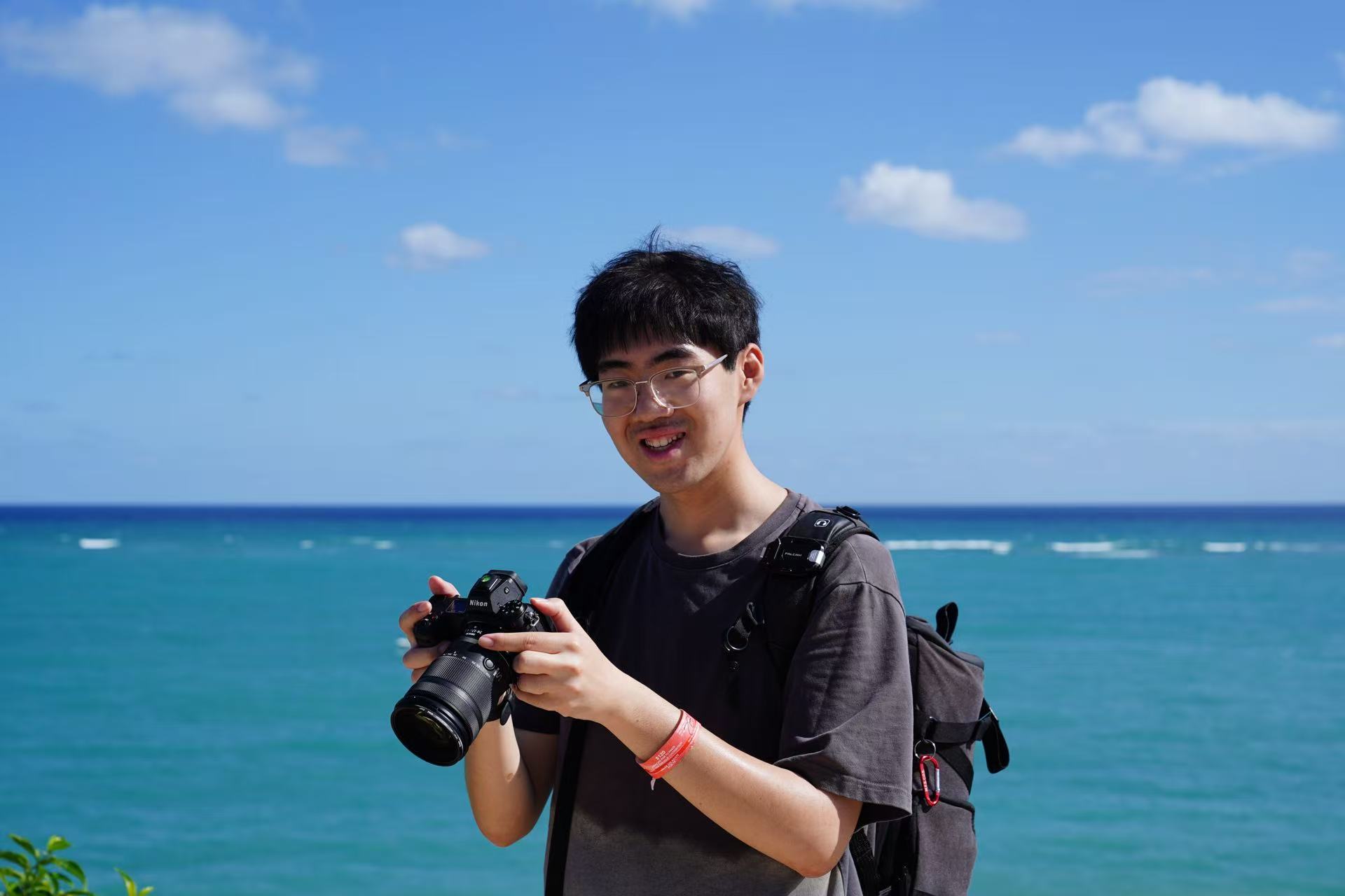 Zhaoji Wang near the ocean holding a camera